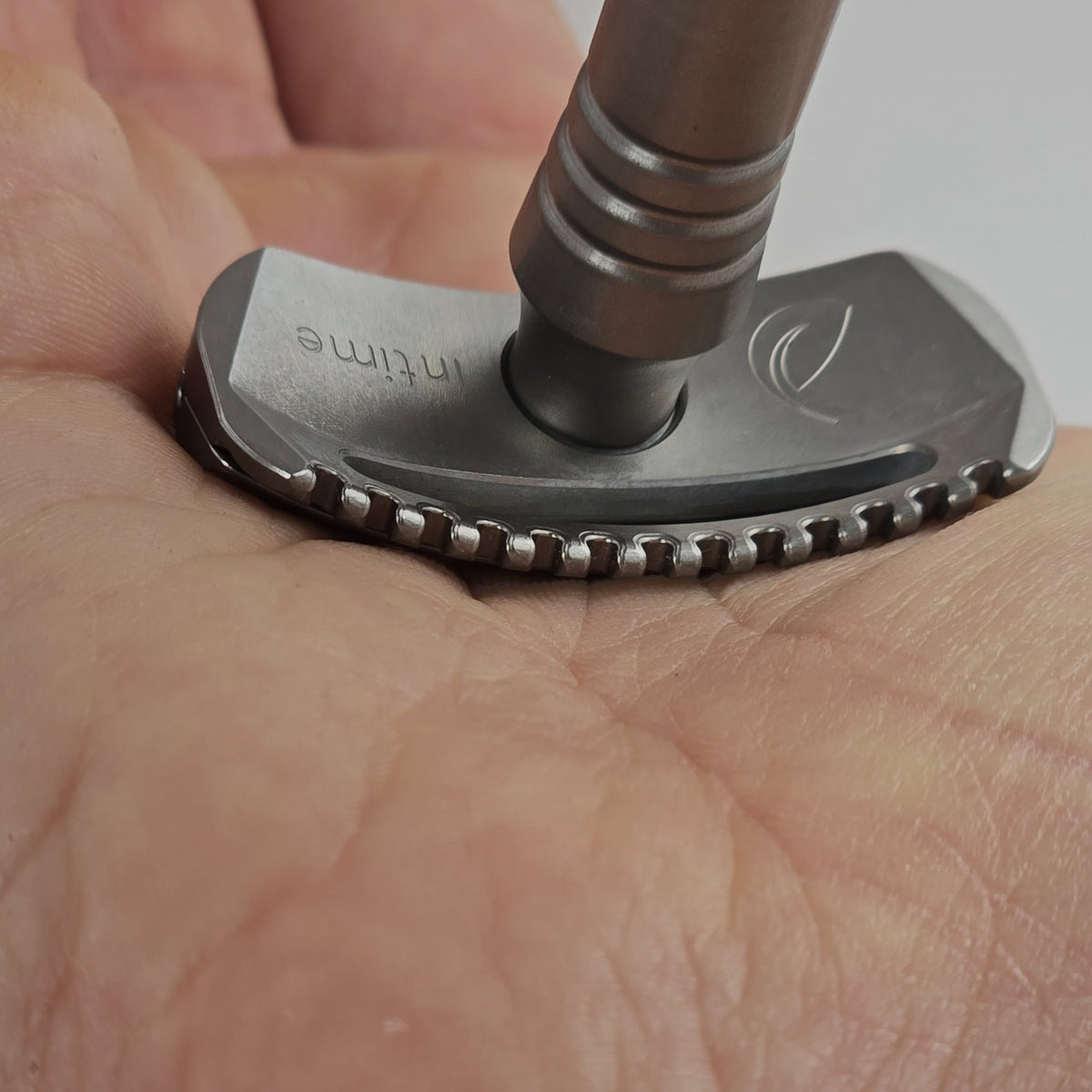 La tête courbe de l’Intime posée dans le creux d’une paume : les dents du peigne suivent la main sans enfoncer la peau.